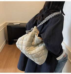 Detail of cream quilted tote bag with contrasting black and white striped shoulder strap
