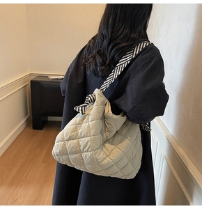 Minimalist beige quilted tote bag with black and white striped knot strap on model back