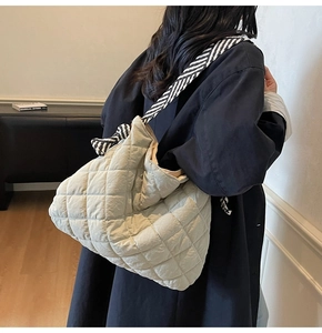 Detail of quilted puffer tote with a stylish black and white striped knotted shoulder strap