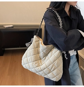 Detail of light beige quilted tote bag featuring a chic black and white braided rope strap