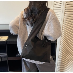 Detail view of the wide shoulder strap and metal ring on black suede crossbody bucket bag