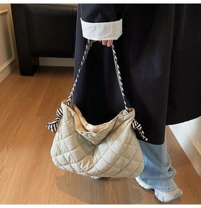 Detail of khaki quilted tote bag with black and white rope handles and knot accents