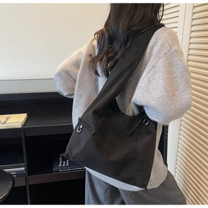 Detailed view of wide shoulder strap and metal ring on matte black tote bag