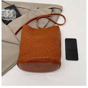 Close-up of brown woven leather bucket bag with adjustable shoulder strap and textured finish