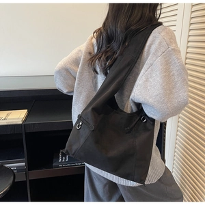 Detail view of a black large capacity crossbody bag with wide shoulder strap and D-ring