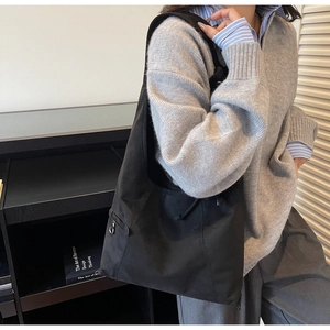 Detail of black suede tote bag with side zipper pocket and drawstring pleat accents
