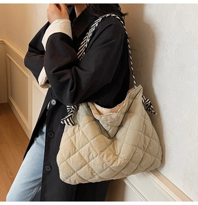 Detail of quilted tote bag with diamond pattern and black-and-white twill strap knot