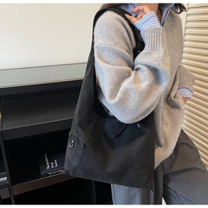 Detailed view of the black suede bucket bag with side drawstring and metal buckle accents