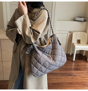 Detail of grey quilted tote bag with black and white striped woven strap and knot decoration
