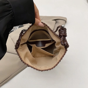 Interior view of the woven shoulder bag showing beige canvas lining and zipper pocket
