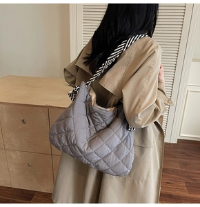 Macro detail of grey quilted tote bag with wide black and white striped shoulder strap