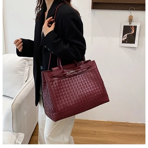 Detail view of burgundy woven tote bag with metallic lock closure and spacious interior