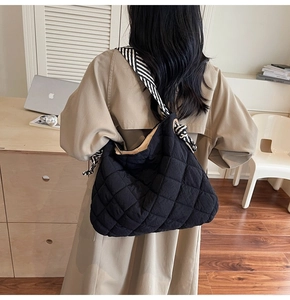 Detail of black quilted tote bag with black and white striped woven wide shoulder strap