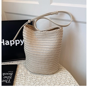 Detailed close-up of cream hand-woven bucket bag featuring premium twill texture