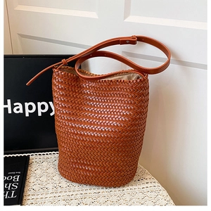 Detail of hand-woven leather bucket bag showing brown woven texture and strap