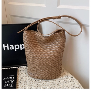 Detailed view of woven brown leather bucket bag featuring adjustable shoulder strap and texture
