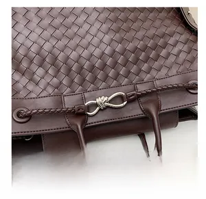 Close-up of woven dark brown leather tote with a silver knotted buckle detail