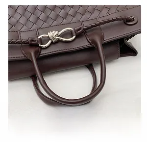 Detail view of dark brown hand-woven leather bag with silver metallic knot hardware