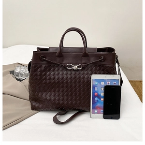 Detailed macro view of deep brown woven leather tote with silver knot buckle and strap