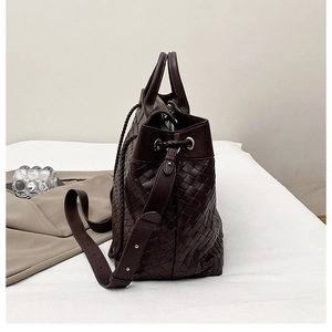 Close-up of dark brown woven leather tote showing side drawstring and rivet strap