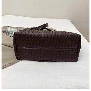 Detailed close-up of dark brown hand-woven leather tote bag with a flat base and strap
