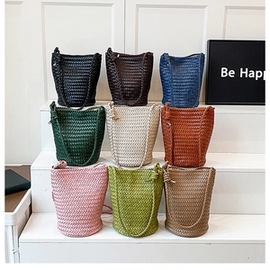 Grid display of nine colorful hand-woven bucket bags on a minimalist white stepped stand