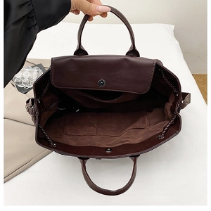 Detail view of large dark brown woven tote bag interior with magnetic closure and soft lining