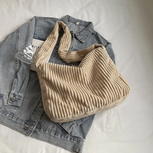 Minimalist beige corduroy tote bag with vertical stripes texture on a denim jacket