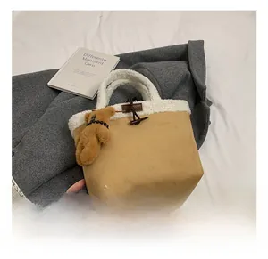 Detail of camel suede handbag with white faux shearling trim and cute plush bear charm