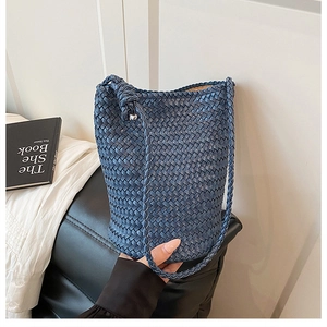 Detail of dark blue hand-woven leather bucket bag showing texture and braided strap