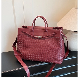 Macro detail of wine red woven leather tote bag with silver knot buckle and texture