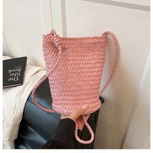 Detail of pink hand-woven bucket bag with minimalist knot and slender shoulder strap