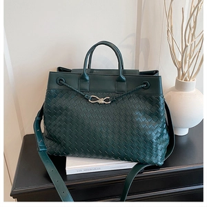 Detail of dark green woven leather tote bag with metal bow buckle and wide strap