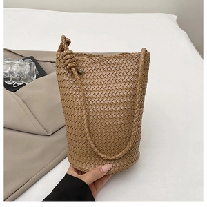 Detail shot of the tan woven bucket bag showcasing the intricate Intrecciato craftsmanship