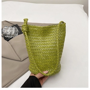 Close-up of olive green woven bucket bag showing intricate leather texture and knotted strap