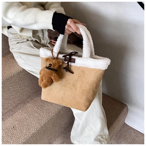 Detail of faux shearling bucket bag with horn button and plush bear charm accent