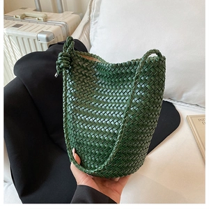 Detailed texture of dark green hand-woven leather bucket bag with knotted shoulder strap