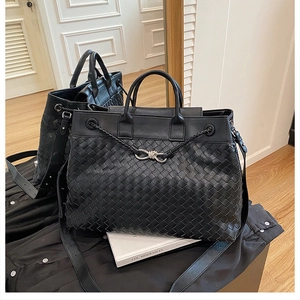 Detail of black woven leather tote bag featuring silver knot buckle and top handles