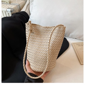 Close-up of beige hand-woven leather bucket bag with thick texture and knotted strap