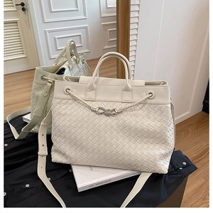 Detail of hand-woven off-white tote bag with silver bow buckle and textured leather finish