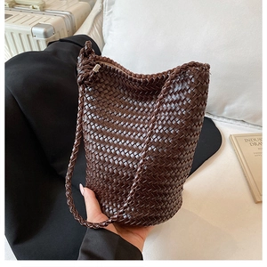 Close-up of deep brown hand-woven leather bucket bag with intricate crisscross texture