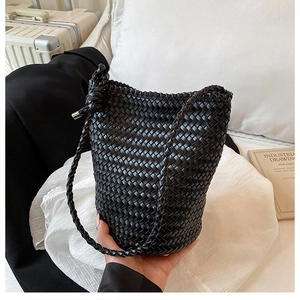 Detail showing the intricate woven texture and knot design on this black bucket bag