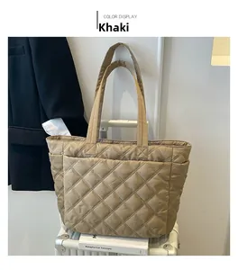Detail of khaki quilted tote bag with diamond pattern placed on a white suitcase