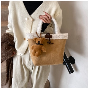 Detail of camel suede tote with white faux shearling trim and horn button accent