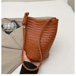 Detail of a brown hand-woven leather bucket bag showing its premium texture and knotted strap