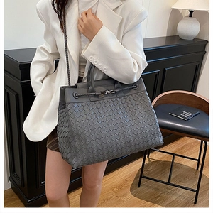 Close-up of hand-woven grey leather tote bag with metal knot clasp and strap detail