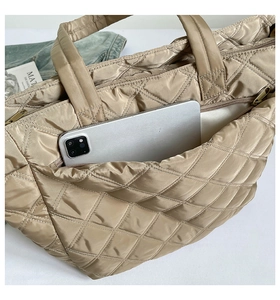 Detail of quilted nylon tote with exterior zipper pocket showing large capacity for tablets