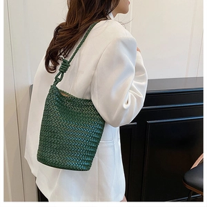 Detail of green hand-woven bucket bag with intricate knit texture and knotted strap