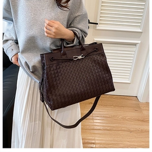 Close-up of dark brown woven leather tote with silver knot buckle and shoulder strap