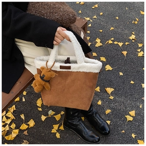 Detail of winter brown suede tote bag with white faux shearling trim and teddy bear charm